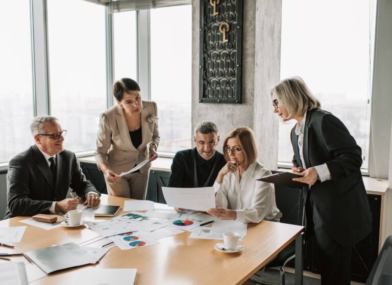 Grupa ludzi siedzi przy stole konferencyjnym. Obrazek w artykule Integracja grupy dorosłych - jak zbudować silny zespół?